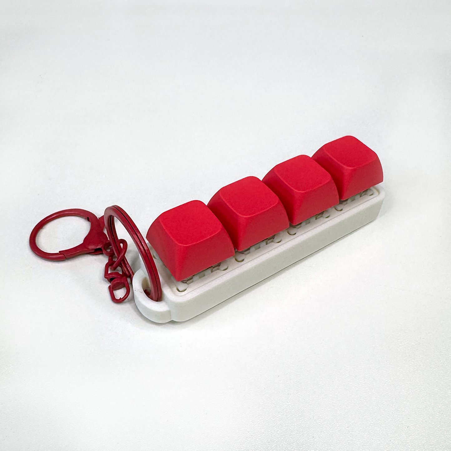 A white four-button clicker fidget keychain with a keychain ring, made with a biodegradable, plant-based plastic.