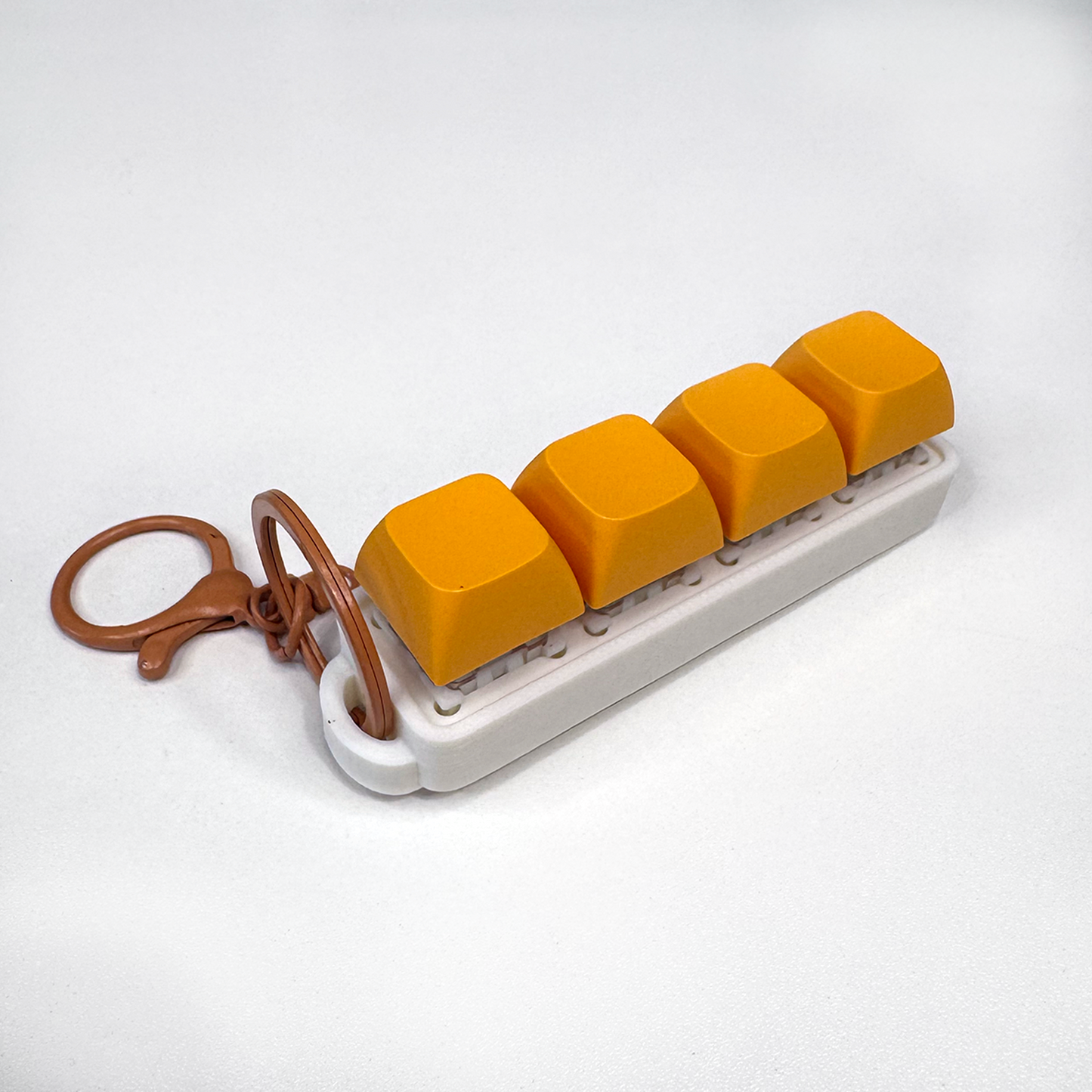 A white four-button clicker fidget keychain with a keychain ring, made with a biodegradable, plant-based plastic.